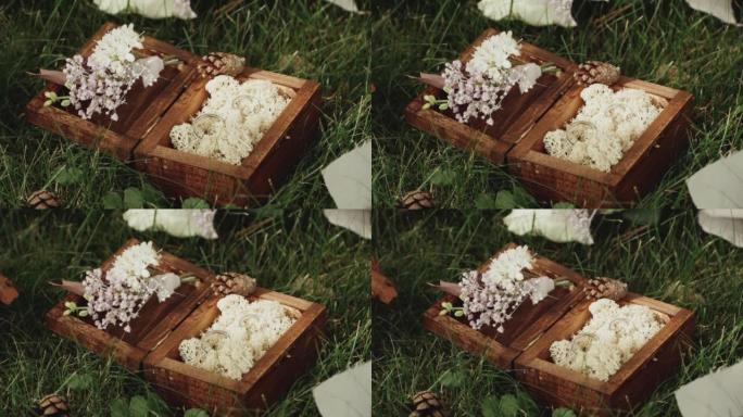 结婚戒指。绿色草坪上的木箱里的结婚戒指装饰着鲜花，慢动作。