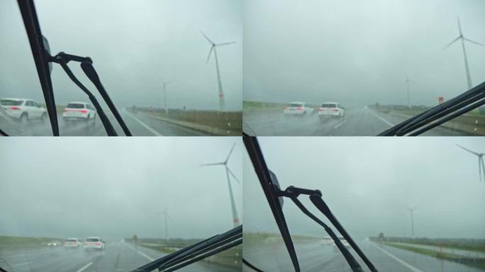 在雨中在高速公路上行驶。雨刮器的特写擦拭汽车雨水湿的挡风玻璃。版本3
