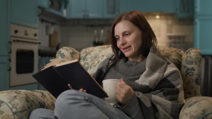 女人在家看书。30多岁的女性喜欢阅读文学作品，坐在舒适的沙发上喝热茶。