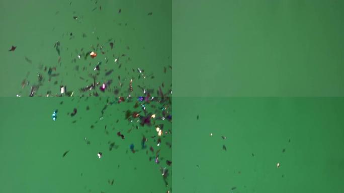 视频4k色彩丰富的派对波普尔掉落在绿屏背景上的五彩纸屑。概念庆祝节日。
