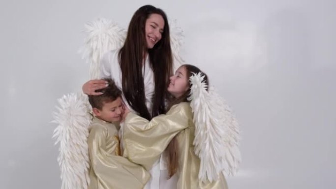 妈妈儿子和女儿穿着天使服装。情人节。拥有白色翅膀的幸福家庭。