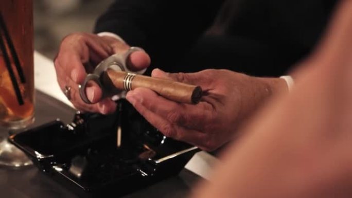 手指上有金戒指的男性手用断头台剪刀剪雪茄