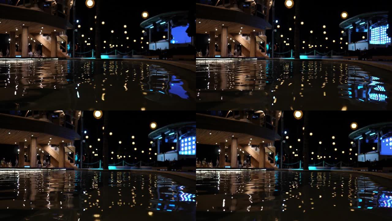 夜间迪斯科舞厅的灯光在游泳池的水面上的反射。假日夜生活照明。准备在豪华酒店的室内游泳池举行泡沫派对。