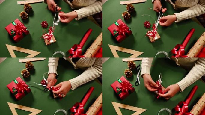 女人的手的俯视图使用剪刀，在绑好圣诞节礼物的同时将白色装饰带切成条状