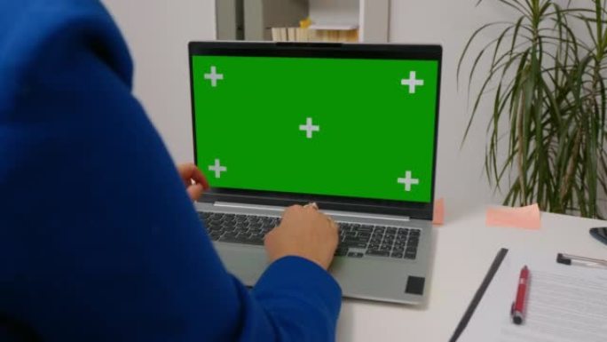 女人坐在笔记本电脑上，模拟绿屏色度键显示。