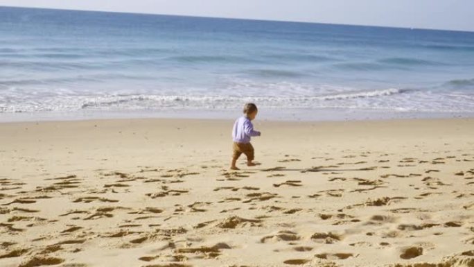 在葡萄牙，一名婴儿学步车发现了沙子并在海滩上散步。