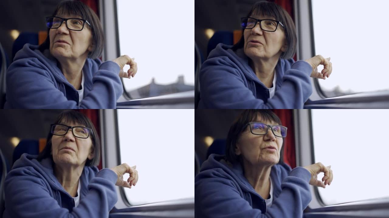 一位戴着眼镜的老妇乘火车坐在窗户附近，与邻居交谈。