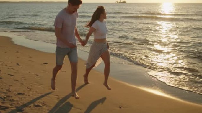 年轻的情侣在日落时在海滩上跑步很开心