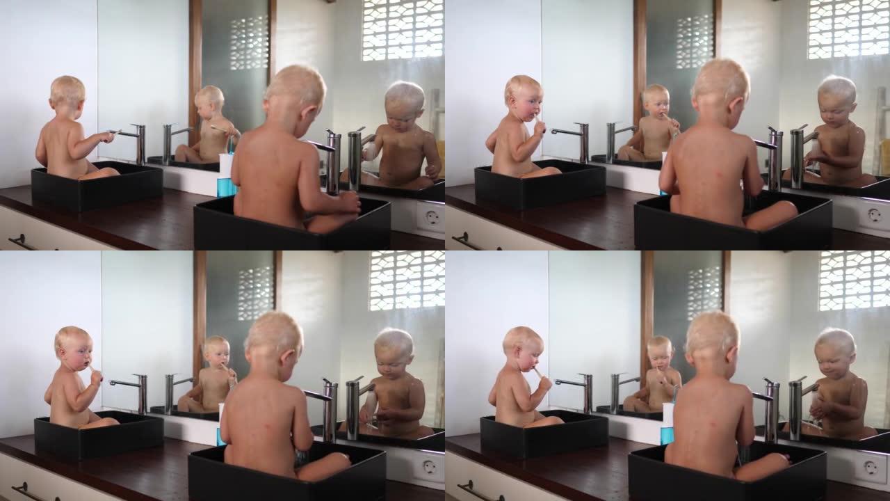 两个高加索双胞胎婴儿各自坐在自己的水槽里，他们像母亲教他们的那样玩水刷牙。他们互相看和复制。