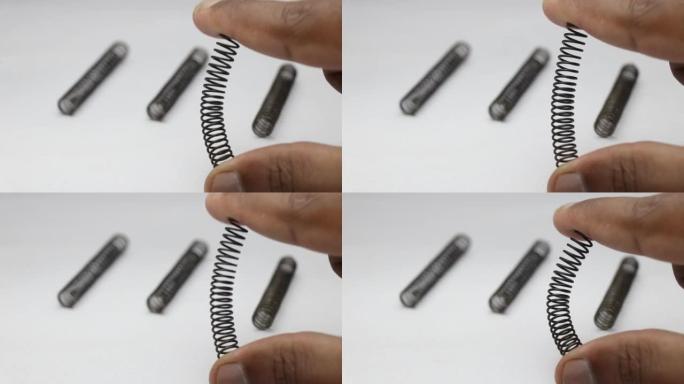 弯曲金属螺旋弹簧以测试其柔韧性。备用金属弹簧尺寸小