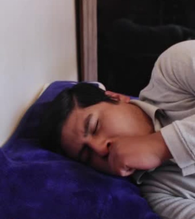 一个西班牙裔男子躺在床上从睡梦中醒来的垂直镜头