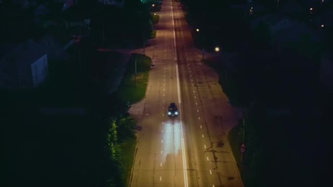 汽车在夜间，郊区，夏天在城市街道上经过减速带。无人机射击。