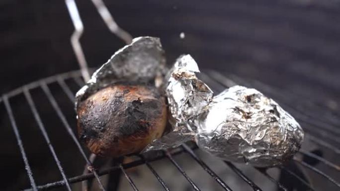 用4k拍摄的烤架上的铝箔烹饪土豆的特写镜头