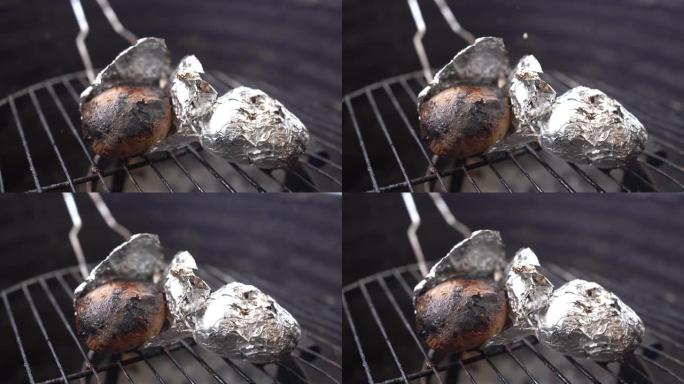 用4k拍摄的烤架上的铝箔烹饪土豆的特写镜头