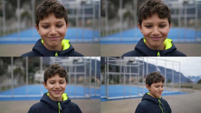 一个快乐的英俊小男孩站在城市公园的户外微笑。穿着冬装的青春期男孩子的肖像脸特写