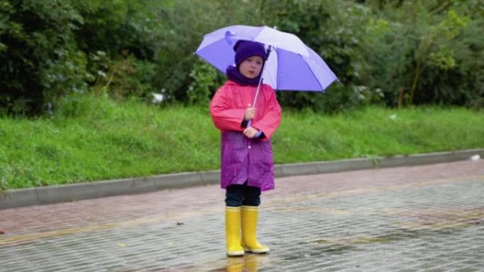 在秋雨中玩耍的孩子。带伞的孩子。任何天气下的户外乐趣。儿童防雨服、靴子和夹克。