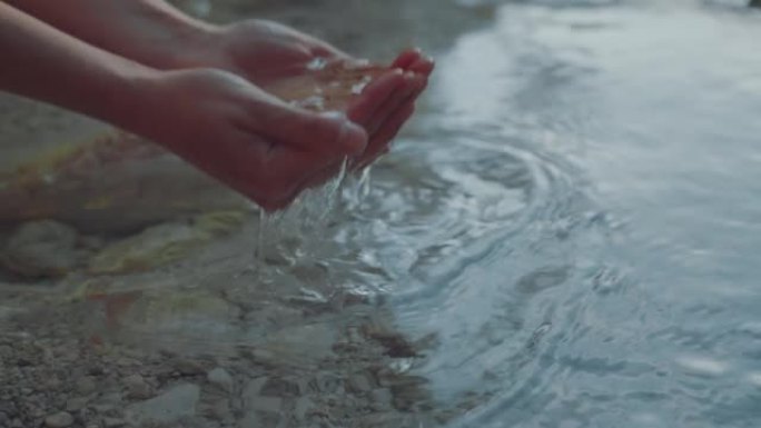 女人的手用纯净的泉水特写镜头。山边新鲜透明的溪水。