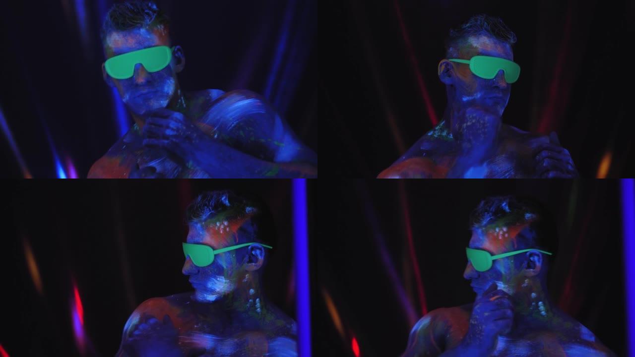 一个戴着绿色眼镜的男人，身上戴着紫外线的图画，在黑暗中跳舞。