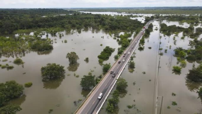 在经过洪水泛滥地区的道路上行驶的交通汽车的鸟瞰图