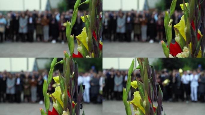 小学和小学的孩子和父母用花束。散焦模糊图像。前景上的一束鲜花。