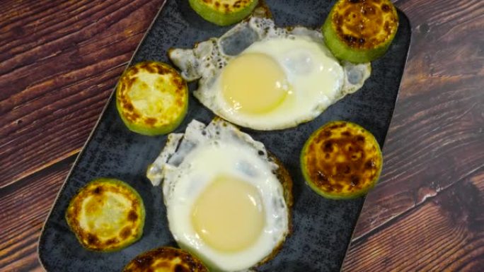 煎鸡蛋和烤西葫芦在盘子上的幻灯片。慢速微距多莉吃一顿开胃的午餐或晚餐。酮饮食减肥概念的元素。