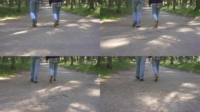 两个人一起走在一条小路上的牛仔裤腿的特写