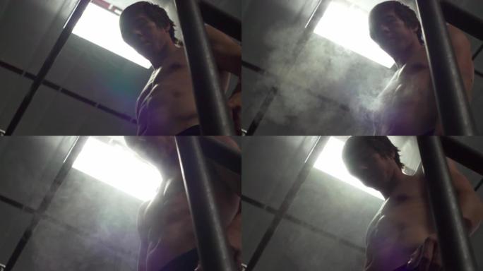 一个性感的年轻男性在健身房给他的手打粉的低角度镜头