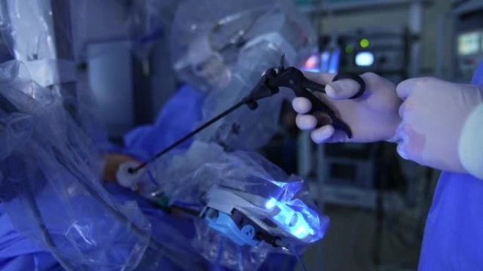 创新的机器人外科医生在现代诊所操作病人。医生的手握着病人体内的黑色长仪器。特写。