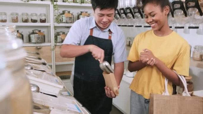 亚洲男店主在笔芯店向女顾客舀零食。