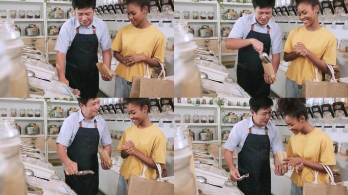 亚洲男店主在笔芯店向女顾客舀零食。
