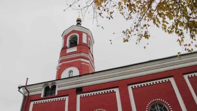 基督教教堂是红色的，有一座高高的钟楼。这座寺庙是在多云的天空下拍摄的