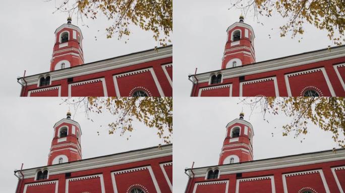 基督教教堂是红色的，有一座高高的钟楼。这座寺庙是在多云的天空下拍摄的