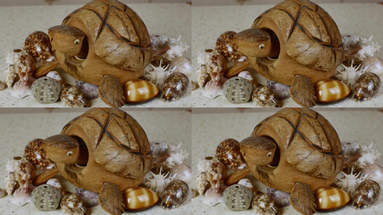 一个由椰子壳制成的乌龟模型摇了摇头，五颜六色的贝壳躺在一张轻便的桌子上，表面像海沙