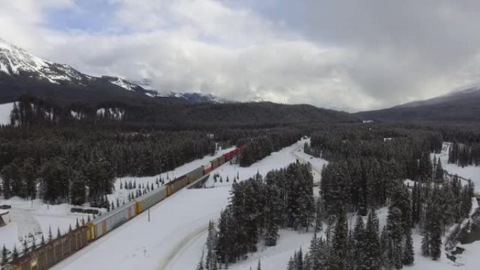 火车在铁路上穿越被山包围的白雪皑皑的加拿大森林的风景照片