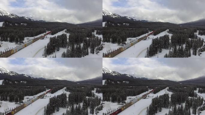 火车在铁路上穿越被山包围的白雪皑皑的加拿大森林的风景照片