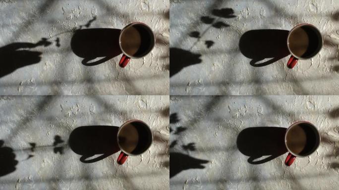 模糊的阴影女性手与花的垃圾背景与咖啡杯。高对比度。抽象，光影的游戏