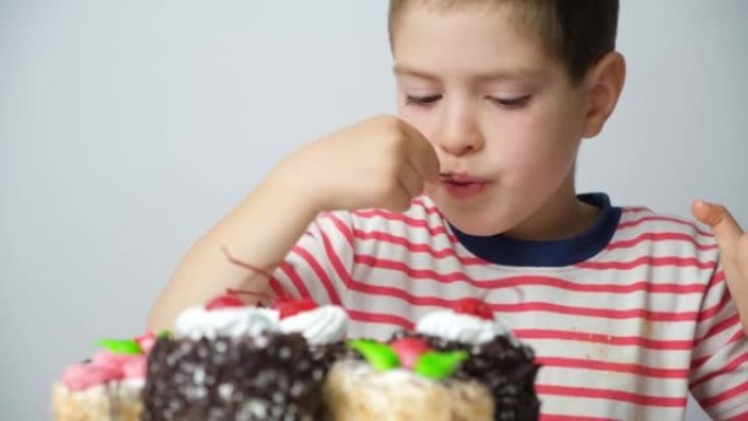 学龄前5岁男孩用勺子吃蛋糕，在白色背景上舔