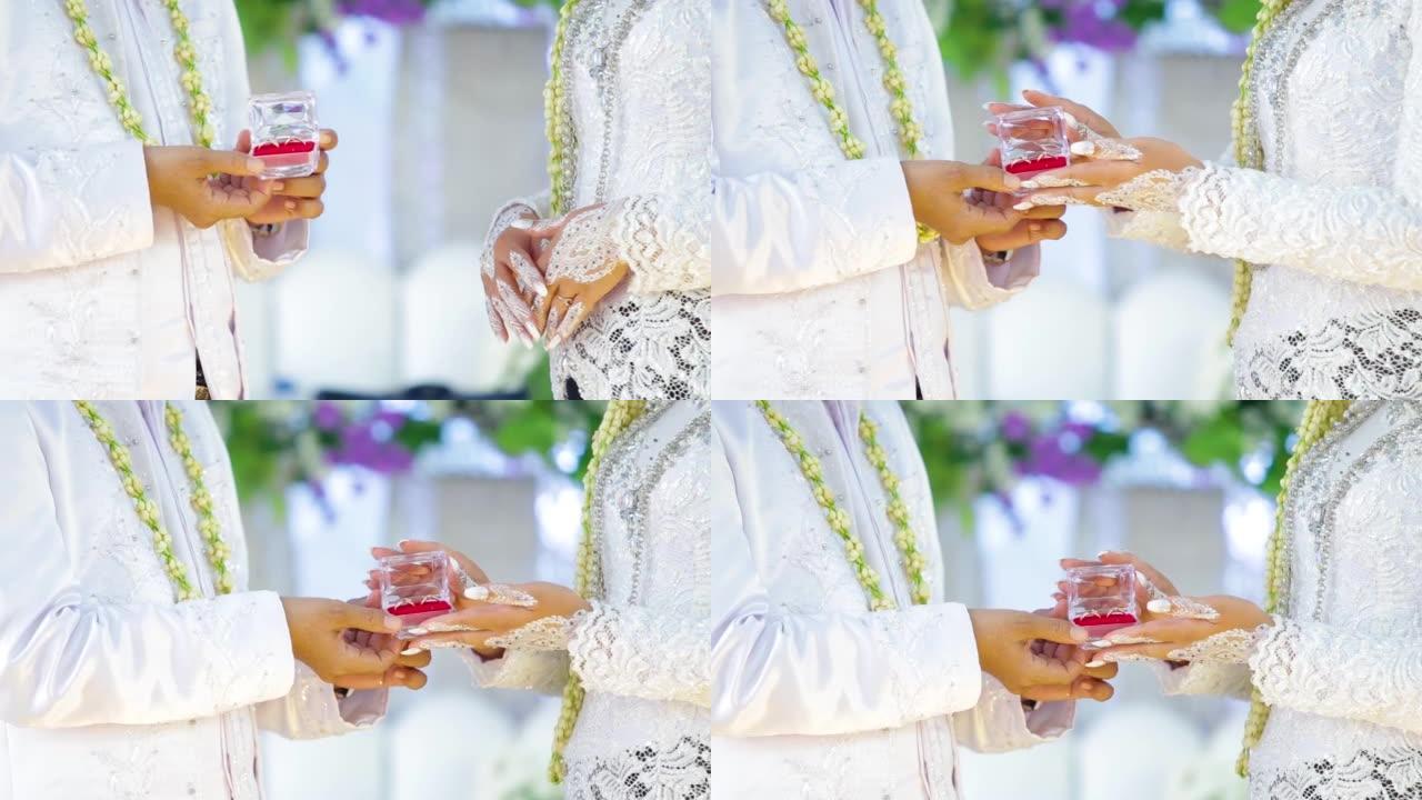 新郎给新娘的嫁妆。印度尼西亚婚礼上的爱情宣言。亲爱的男性拿着手里拿着钻戒的小盒子的特写向心爱的年轻女