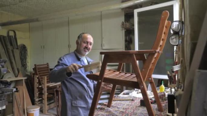 他车间里的一个木匠组装了一把手工制作的椅子，拧上螺栓，用六角扳手固定。检查椅子的强度。家居装饰用木制