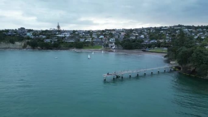 下降的无人机在海上的一个长码头上射击，地平线上有城市景观