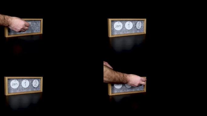 一个木制日历块，用男人的手1月12日和取下带有日期和月份的金属盘，以4k质量拍摄
