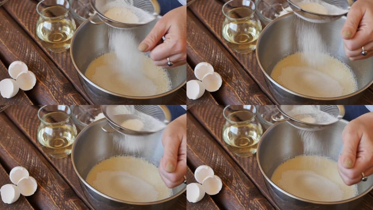 在准备煎饼面团的过程中，妇女手持筛子的手将面粉筛入碗中。以慢动作将小麦粉筛入面糊中。煎饼的制作过程