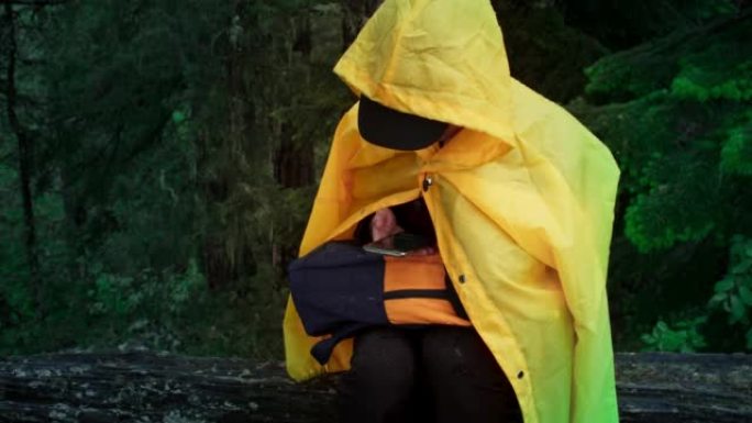 穿着黄色雨衣的不快乐女徒步旅行者躲雨