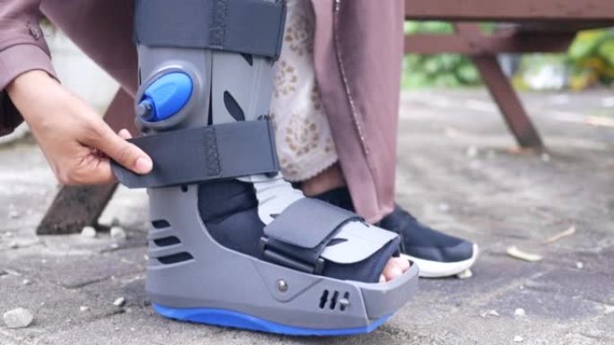 妇女断脚与灰色塑料靴子脚踝支撑受伤保护靴