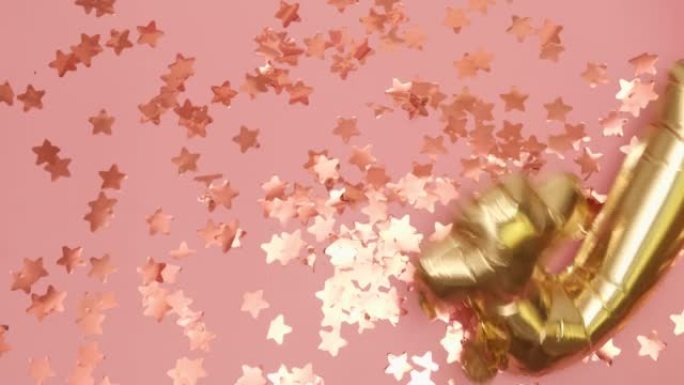 四个形状的金色气球落在带有星星的粉红色地板上
