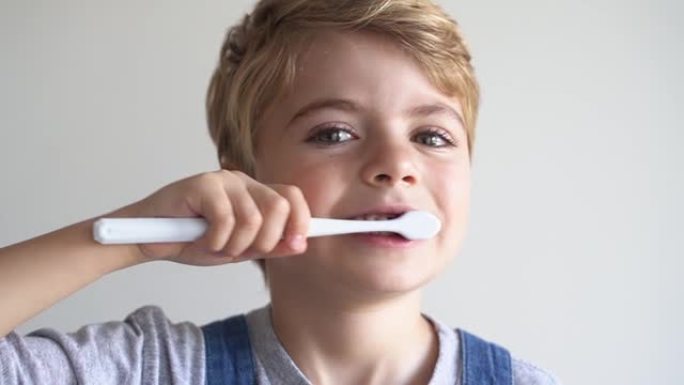 可爱的孩子刷牙牙刷，在白色背景上微笑。工作室拍摄。牙齿卫生，早晨常规，生活方式，牙齿护理，儿童健康。