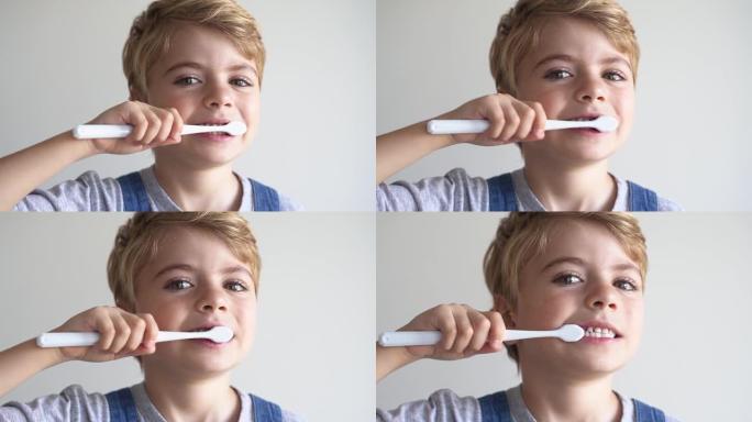 可爱的孩子刷牙牙刷，在白色背景上微笑。工作室拍摄。牙齿卫生，早晨常规，生活方式，牙齿护理，儿童健康。