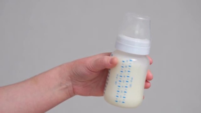 母亲用婴儿配方奶粉摇透明奶瓶