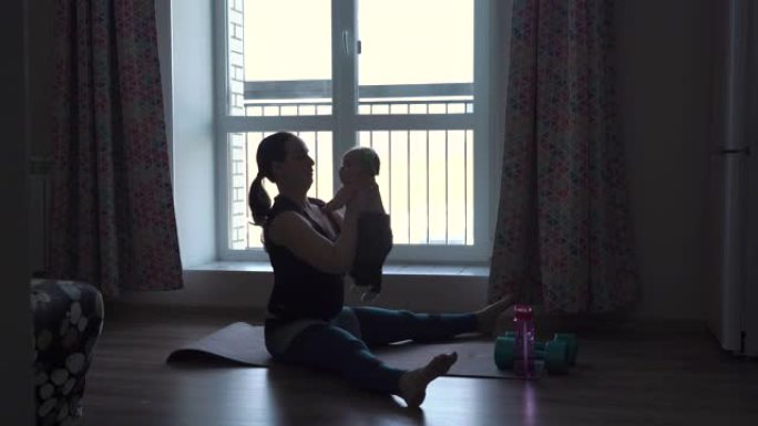 年轻女子与婴儿一起锻炼的剪影