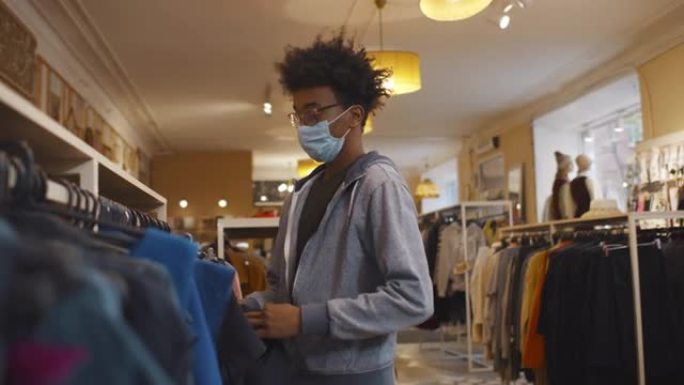 商店里戴着安全面具的非裔美国人选择衣服和偷东西。实时
